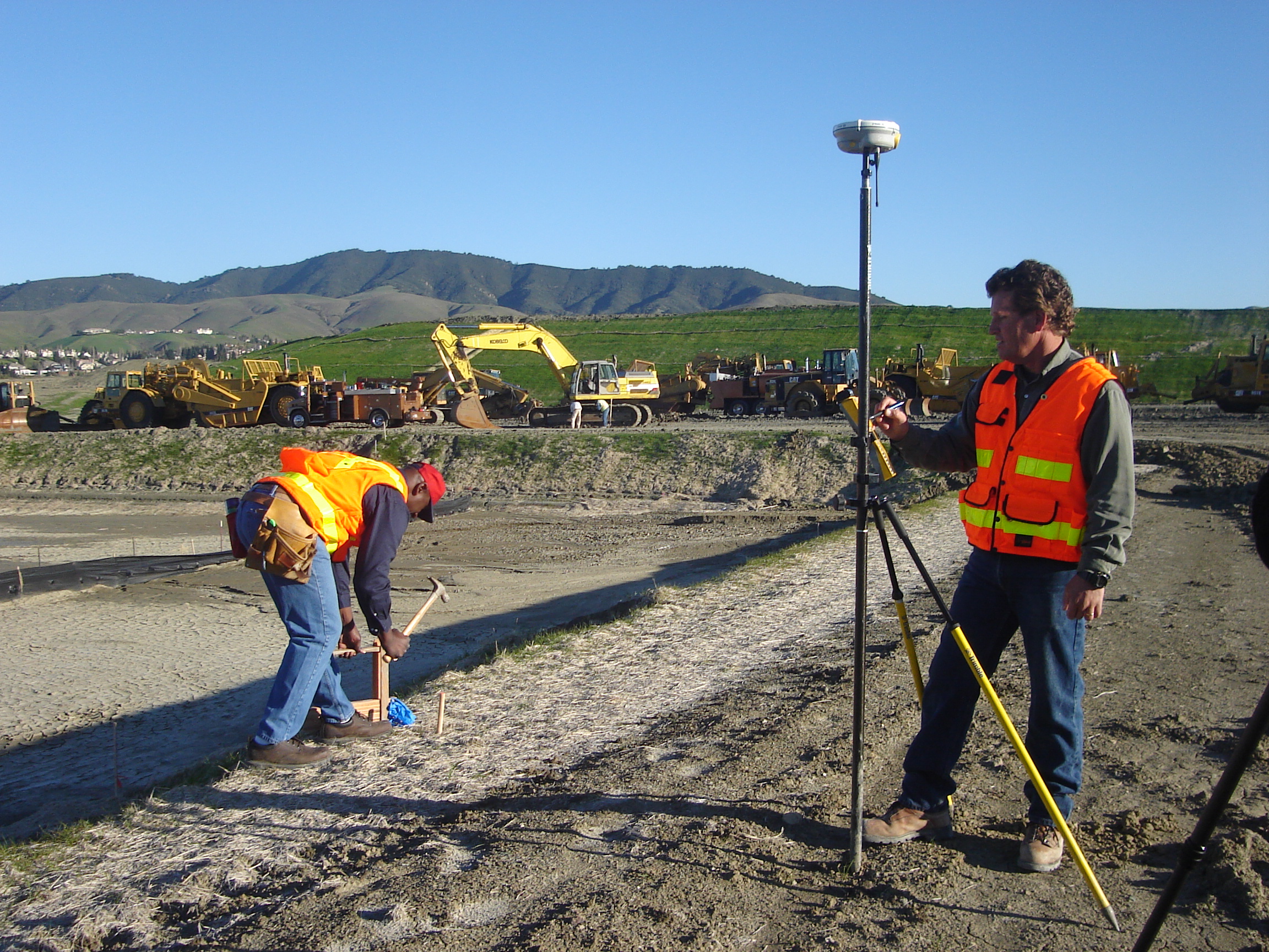 Surveyors at a construction site driving stakes